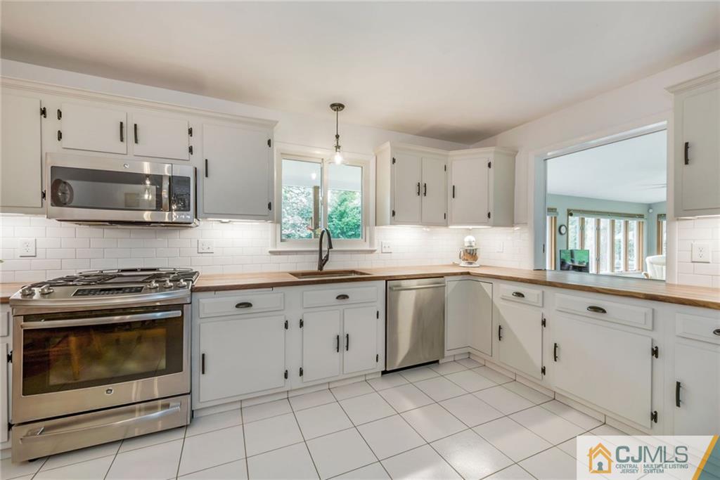 1 Ryan Road Cranbury, NJ 08512 - Photo 6 of 22 a kitchen with granite countertop white cabinets a sink a stove a microwave and a window