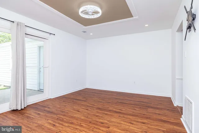 a view of a white house with a small yard and large tree