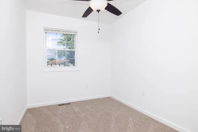 an empty room with a ceiling fan and a window