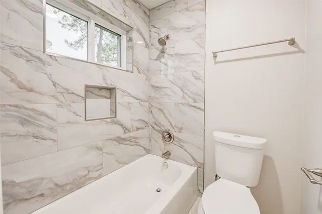 a white toilet sitting next to a white bath tub