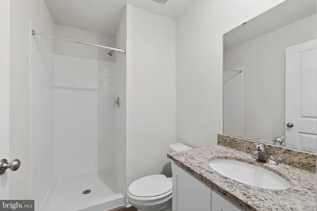 a bathroom with a granite countertop shower and a toilet