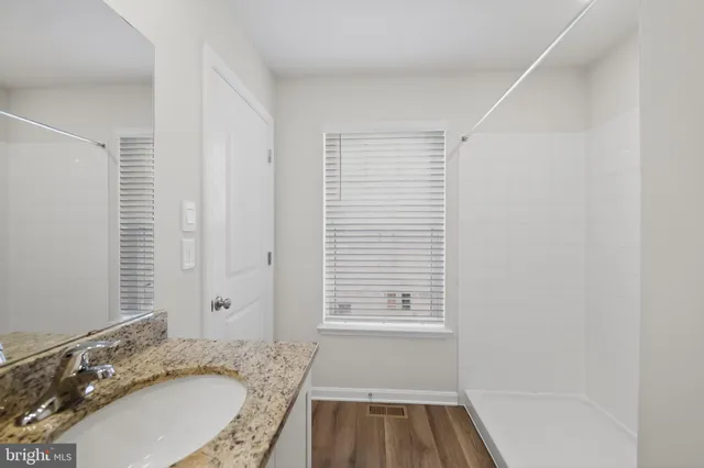 a bathroom with a granite countertop toilet a sink and a mirror