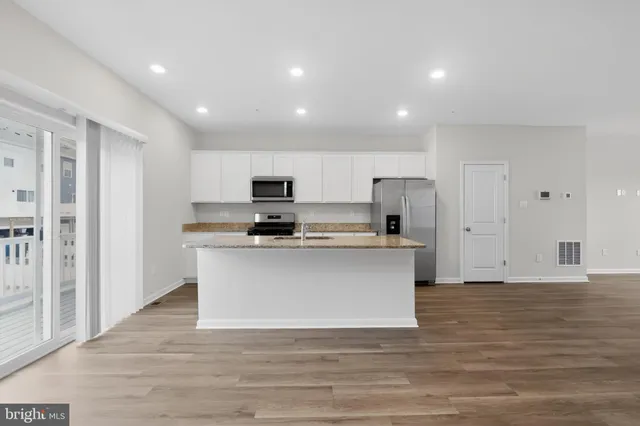 a view of kitchen with microwave stove refrigerator and cabinets