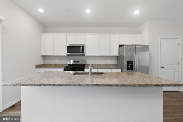 a kitchen with stainless steel appliances granite countertop a sink a stove a microwave and a refrigerator