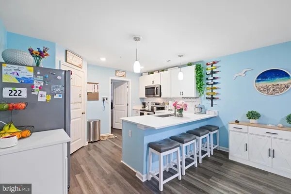 a kitchen with stainless steel appliances a stove a refrigerator a kitchen island with wooden floor