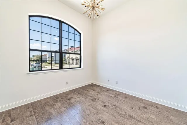 an empty room with chandelier fan and windows