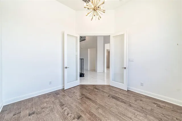 an empty room with wooden floor and kitchen view