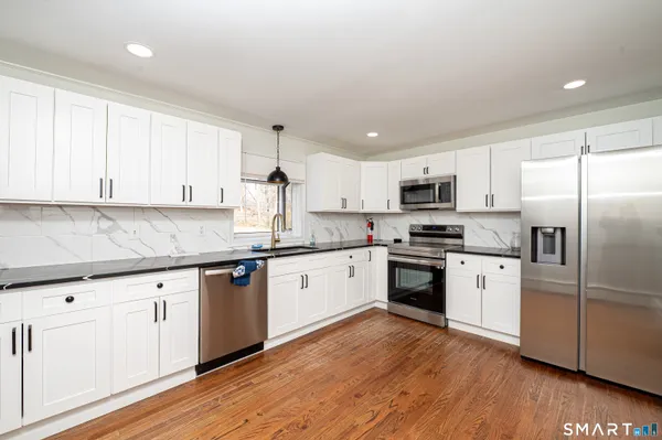 a kitchen with granite countertop a sink cabinets and wooden floor
