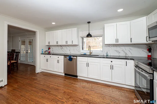 a kitchen with granite countertop a sink cabinets and wooden floor
