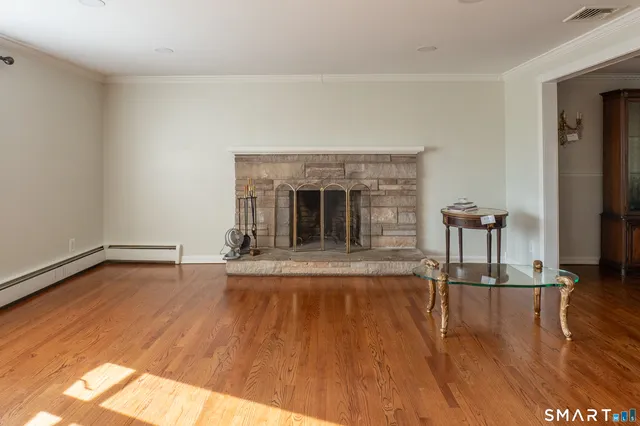 a view of empty room with wooden floor and fireplace