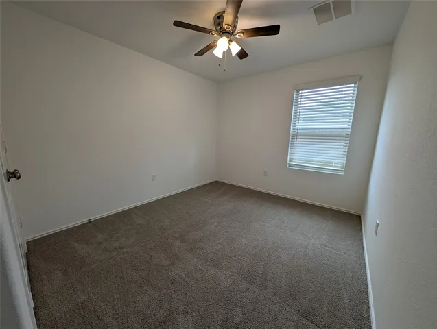 an empty room with a window and a fan