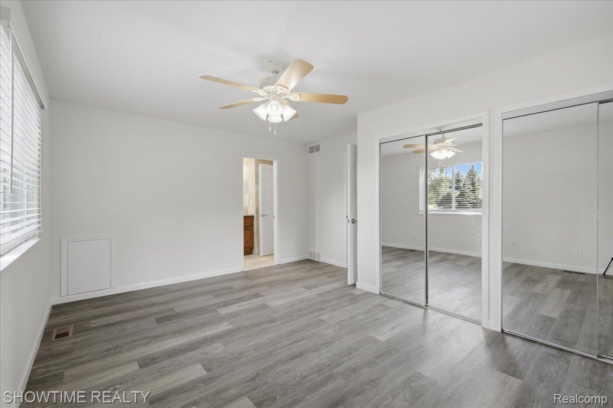 29255 Utley Road Farmington, MI 48334 - Photo 26 of 46 Light-filled room featuring wood-finish flooring, a ceiling fan with light fixture, and mirrored closet doors