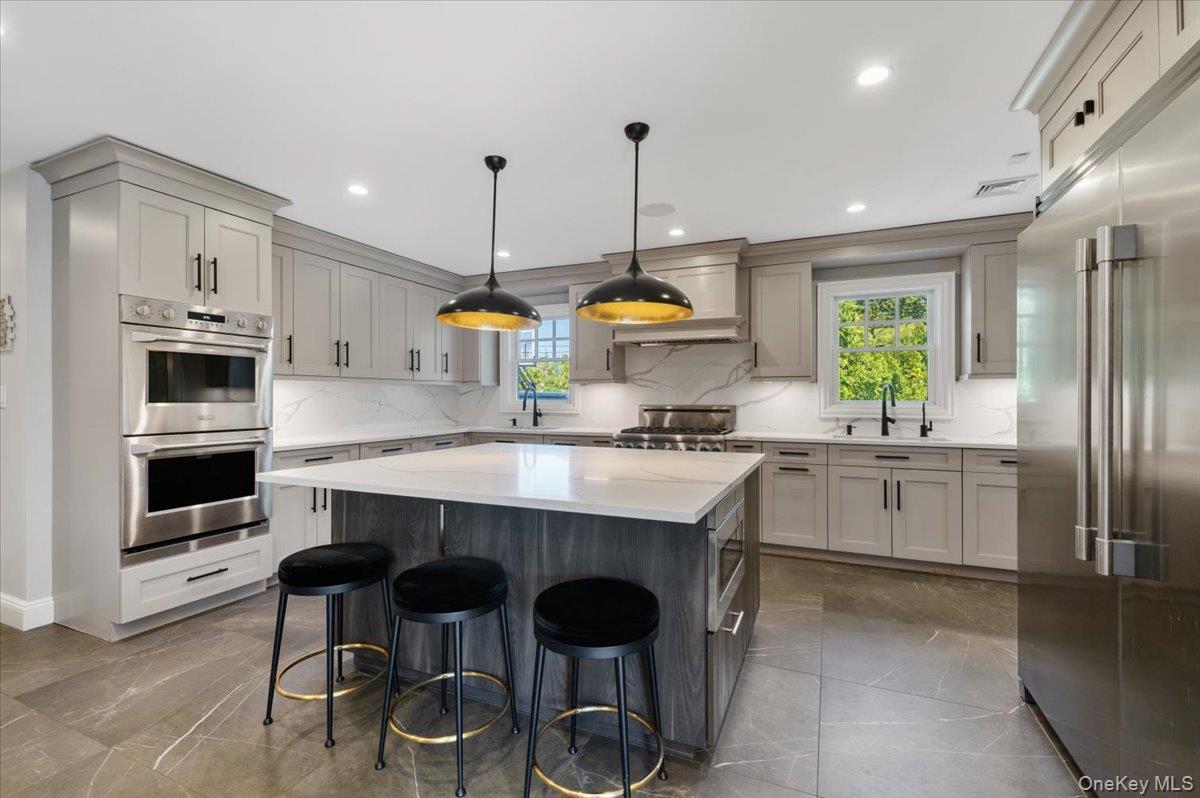 205 Hewlett Neck Road Woodmere, NY 11598 - Photo 12 of 50 a kitchen with kitchen island granite countertop a table chairs sink and cabinets