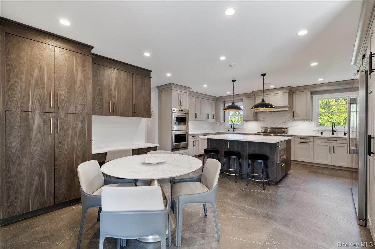 205 Hewlett Neck Road Woodmere, NY 11598 - Photo 13 of 50 a kitchen with kitchen island a dining table chairs and white cabinets