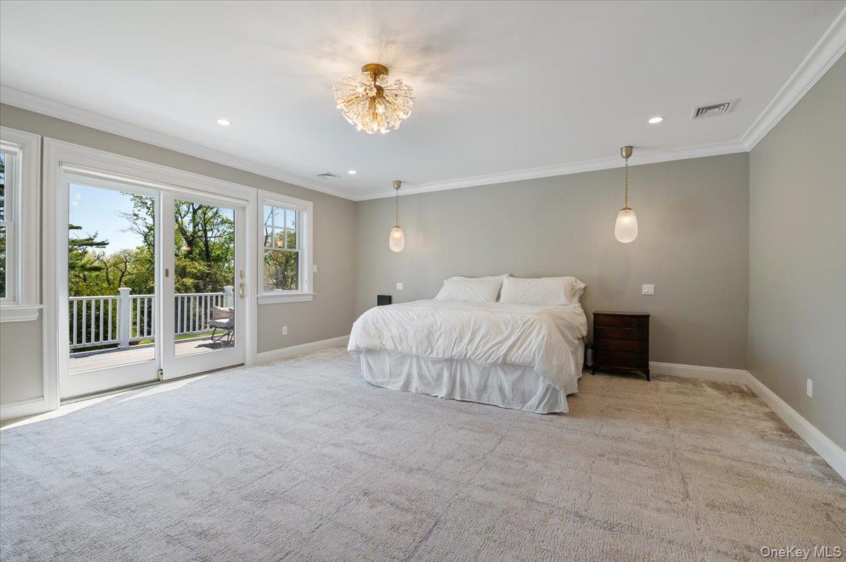 205 Hewlett Neck Road Woodmere, NY 11598 - Photo 35 of 50 a spacious bedroom with a large bed and a chandelier