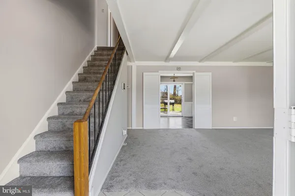 a view of an empty room with wooden floor and stairs