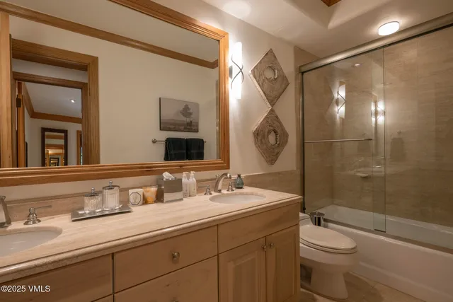 a bathroom with a granite countertop sink a toilet a mirror and shower