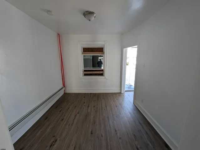 a view of a hallway with wooden floor and a kitchen