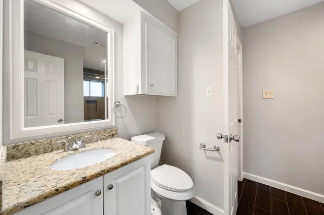 a bathroom with a granite countertop sink and a toilet
