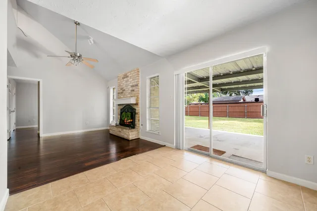 an empty room with floor to ceiling windows and ceiling fan