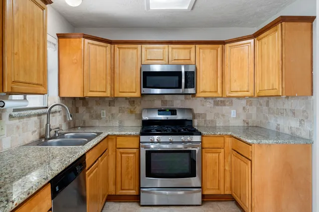 a kitchen with granite countertop a stove a sink and a microwave