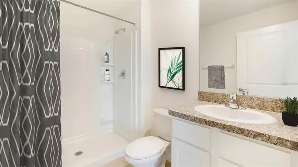 a bathroom with a granite countertop sink a toilet and shower