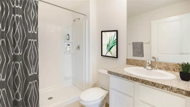 a bathroom with a granite countertop sink a toilet and shower