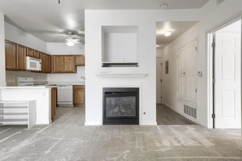a living room with stainless steel appliances granite countertop a fireplace and a refrigerator