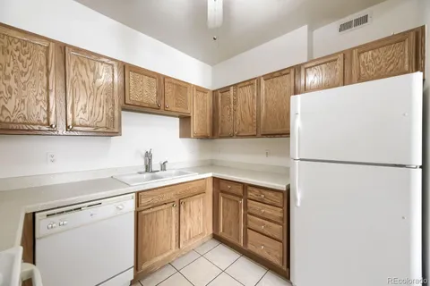 a white refrigerator freezer sitting inside of a kitchen with stainless steel appliances granite countertop white cabinets and white appliances