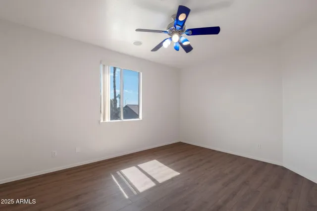 an empty room with wooden floor chandelier fan and windows