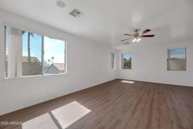 an empty room with wooden floor and ceiling fan