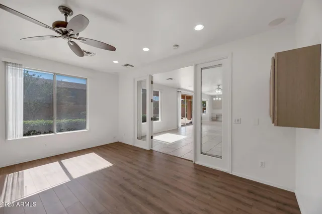 an empty room with chandelier fan and windows