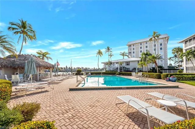 a view of a swimming pool with a lawn chairs under an umbrella