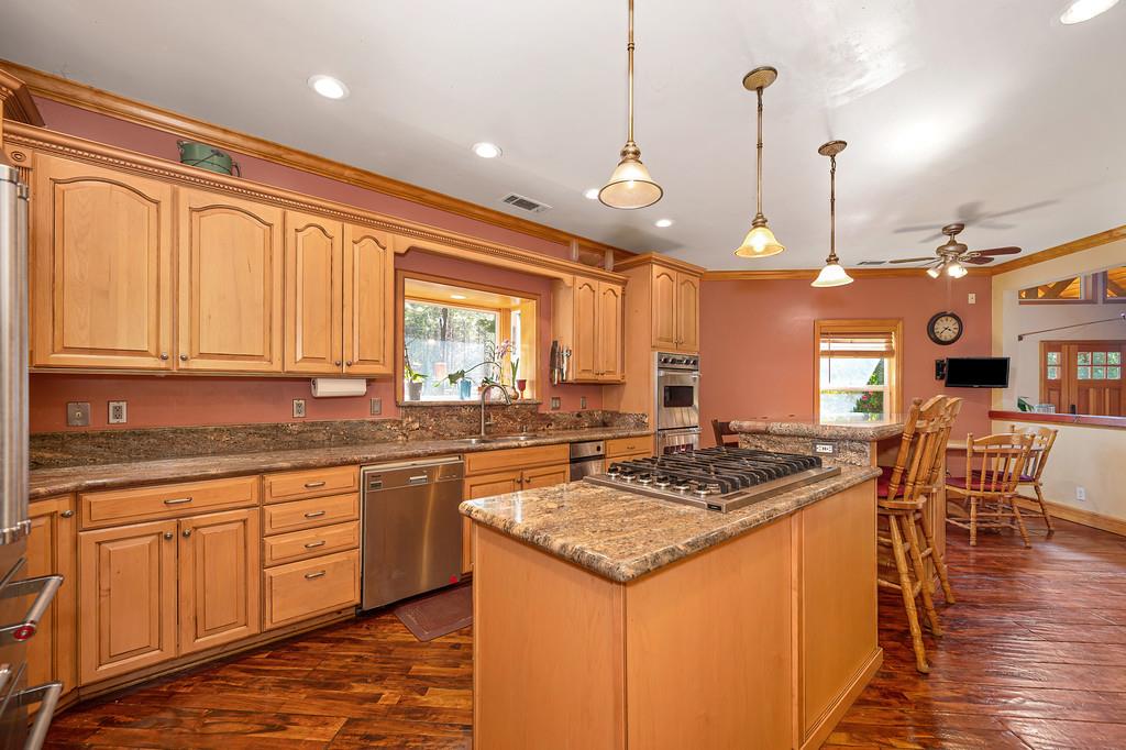 701 Sawmill Road Alta, CA 95701 - Photo 17 of 53 a kitchen with stainless steel appliances granite countertop a stove a sink dishwasher and white cabinets with wooden floor