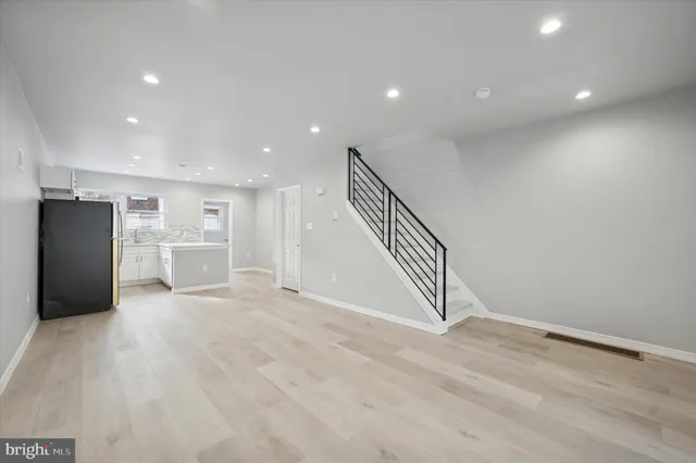a view of an empty room with wooden floor and staircase