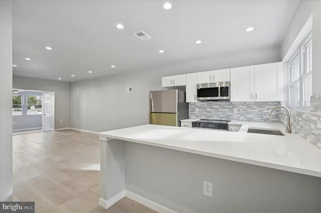 a large kitchen with stainless steel appliances a large counter top a stove and a sink