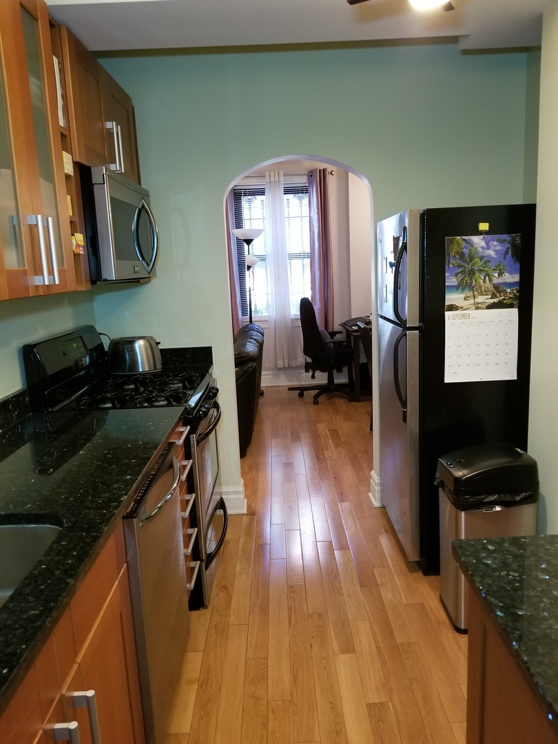 433 West Briar Place, Unit 1D Chicago, IL 60657 - Photo 5 of 12 a kitchen with wooden floor and cabinets