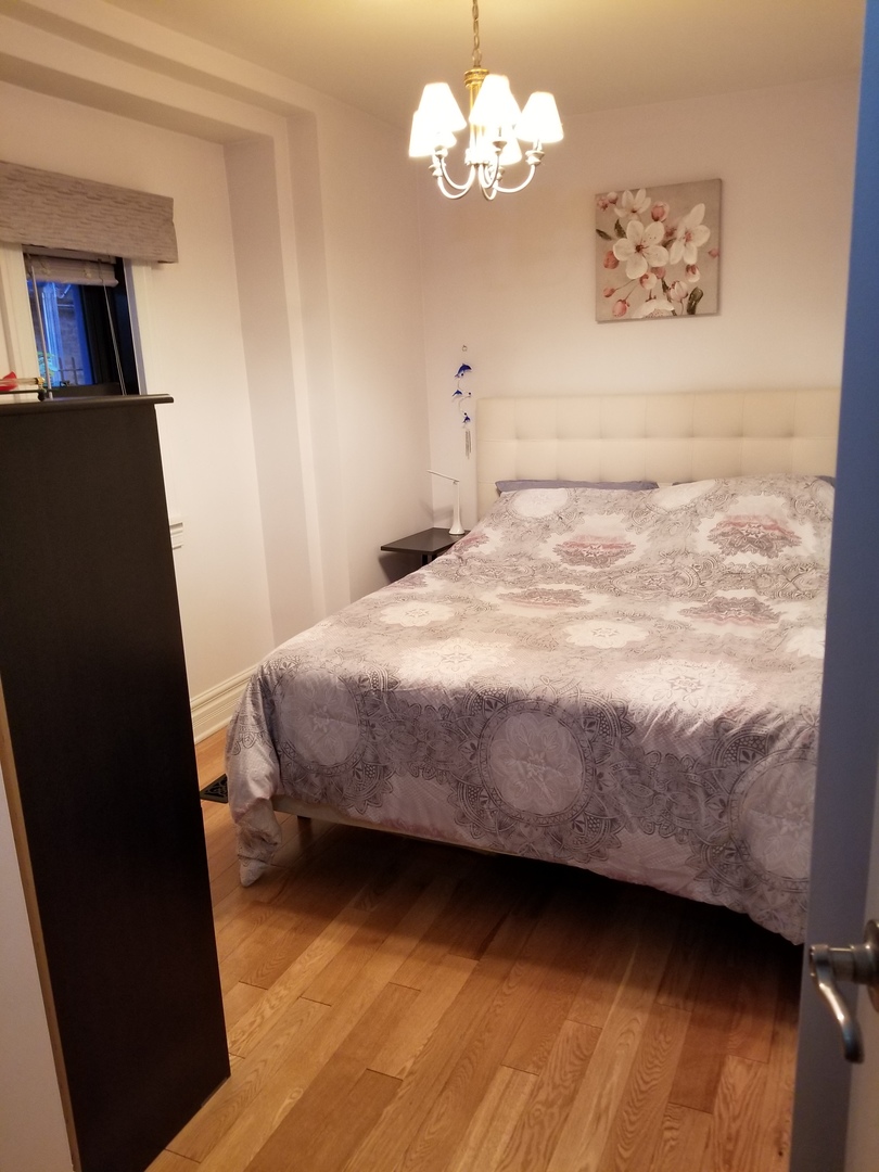 433 West Briar Place, Unit 1D Chicago, IL 60657 - Photo 6 of 12 a bedroom with a bed and a chandelier