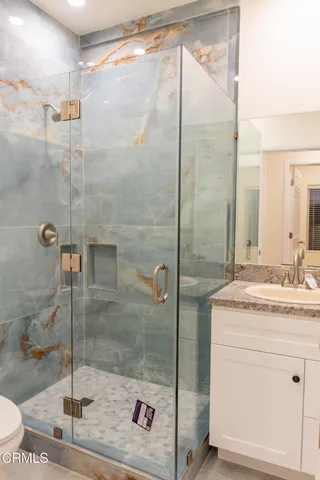 a bathroom with a granite countertop sink a mirror and shower