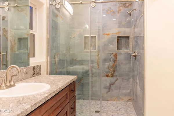 a bathroom with a granite countertop shower a sink and a mirror