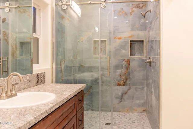 a bathroom with a granite countertop shower a sink and a mirror