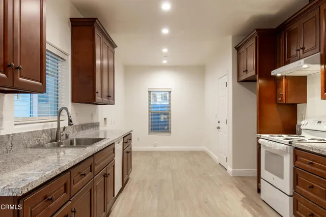 a kitchen with granite countertop a sink stove and cabinets