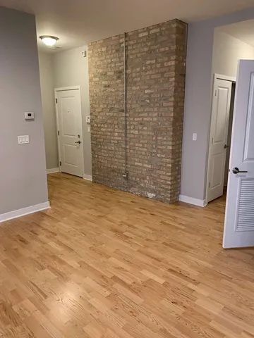 a view of an empty room with wooden floor and a bathroom