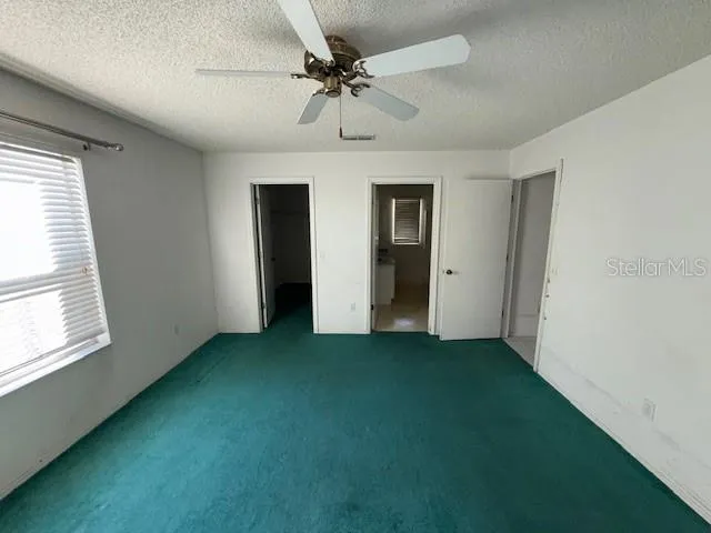 an empty room with fan and windows