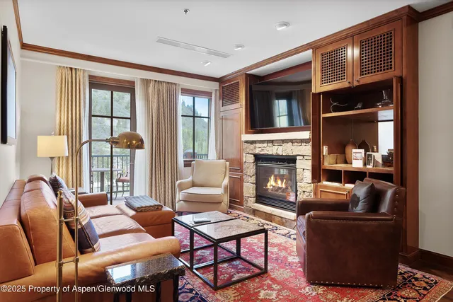 a living room with furniture a fireplace and large windows