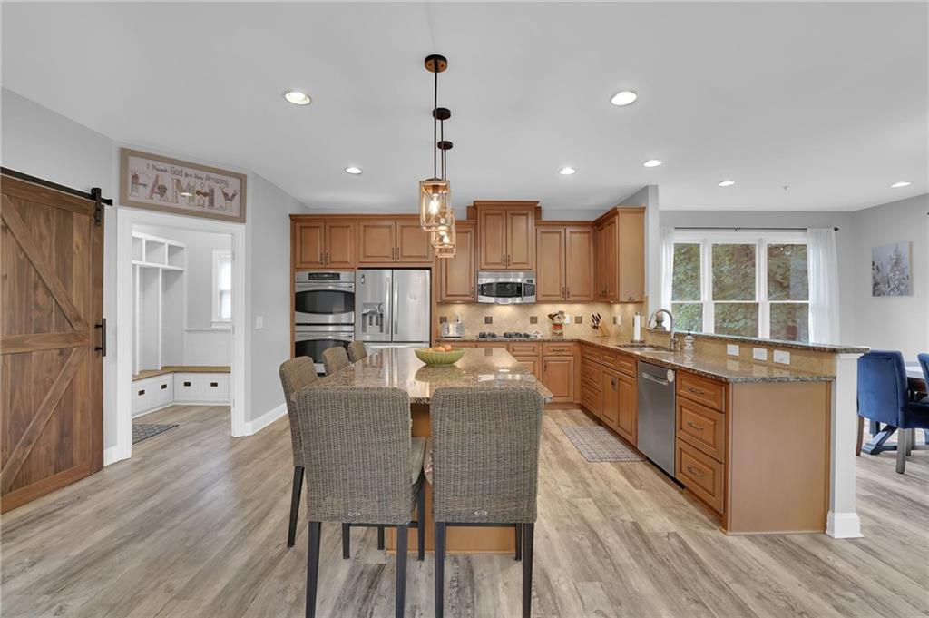 6010 Anchorage Quay Cumming, GA 30041 - Photo 21 of 72 a large kitchen with stainless steel appliances kitchen island granite countertop a large kitchen island a stove a refrigerator a sink a dining table and chairs