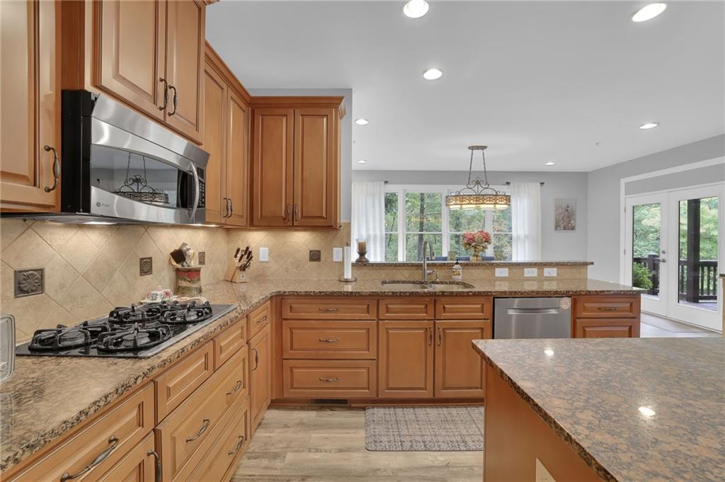 6010 Anchorage Quay Cumming, GA 30041 - Photo 24 of 72 a kitchen with stainless steel appliances granite countertop wooden cabinets stove top oven and sink