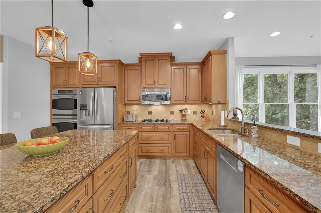 6010 Anchorage Quay Cumming, GA 30041 - Photo 25 of 72 a kitchen with stainless steel appliances granite countertop a sink a stove and a wooden floors