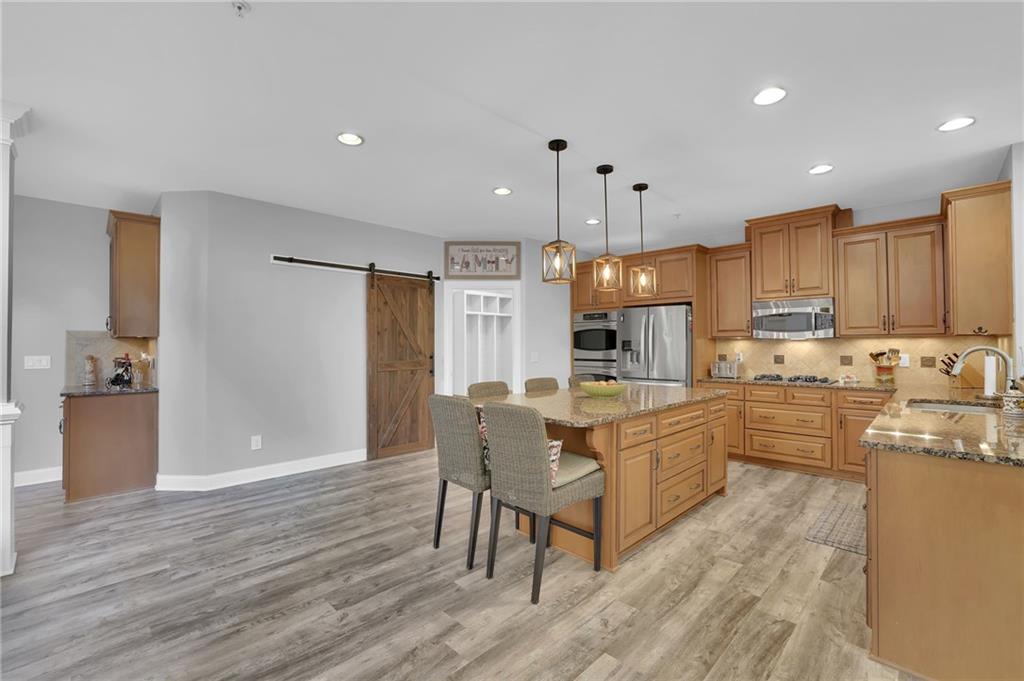 6010 Anchorage Quay Cumming, GA 30041 - Photo 27 of 72 a kitchen with kitchen island granite countertop wooden floors and stainless steel appliances