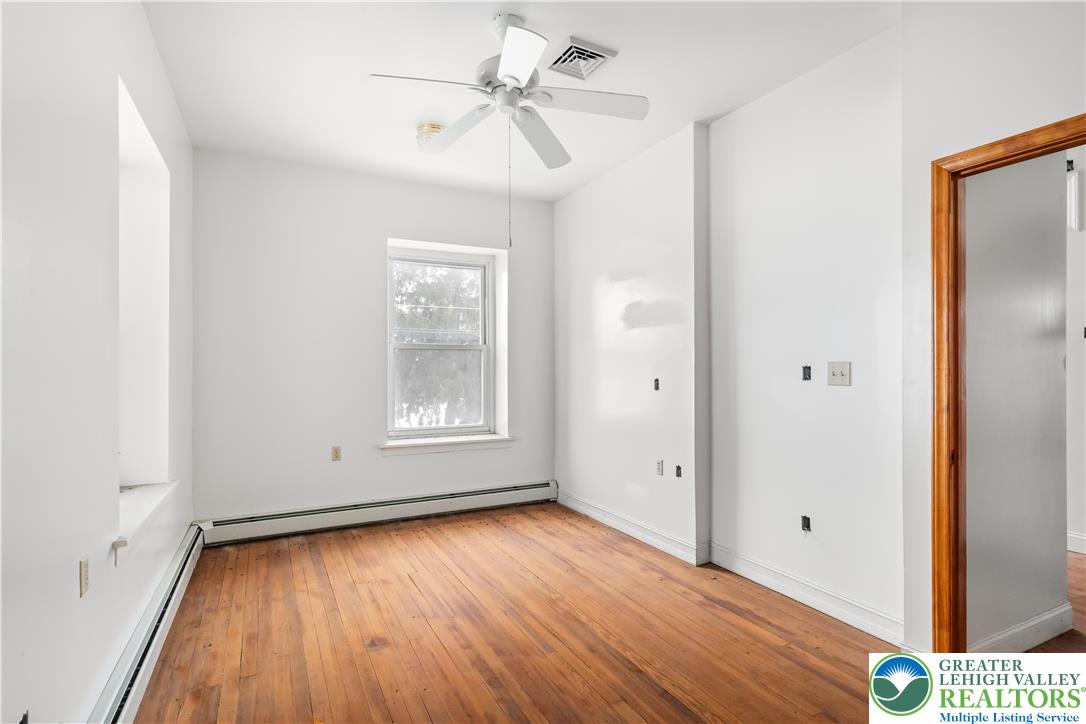 384 Evansville Road Fleetwood, PA 19522 - Photo 21 of 54 an empty room with wooden floor chandelier fan and windows